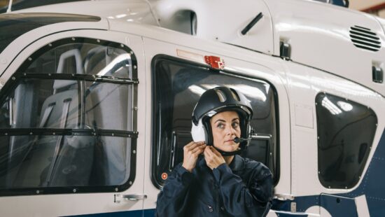 Pilot girl poses with her helicopter wearing helmet